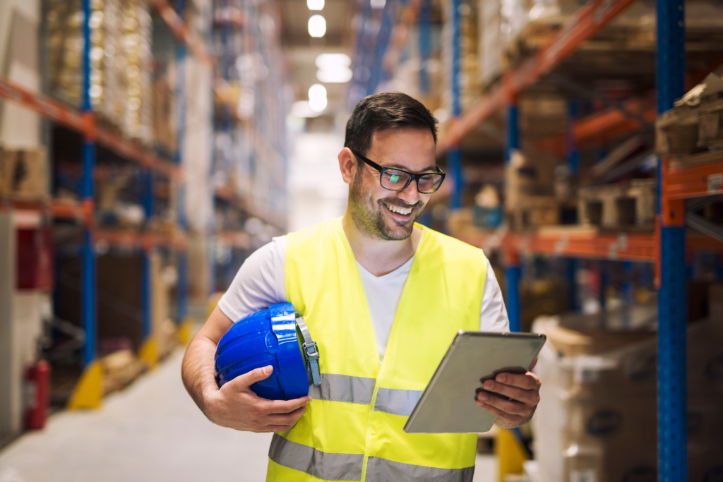 Trabajador de primera línea utilizando una tablet en un almacén, optimizando sus tareas con los planes Microsoft 365 Frontline.